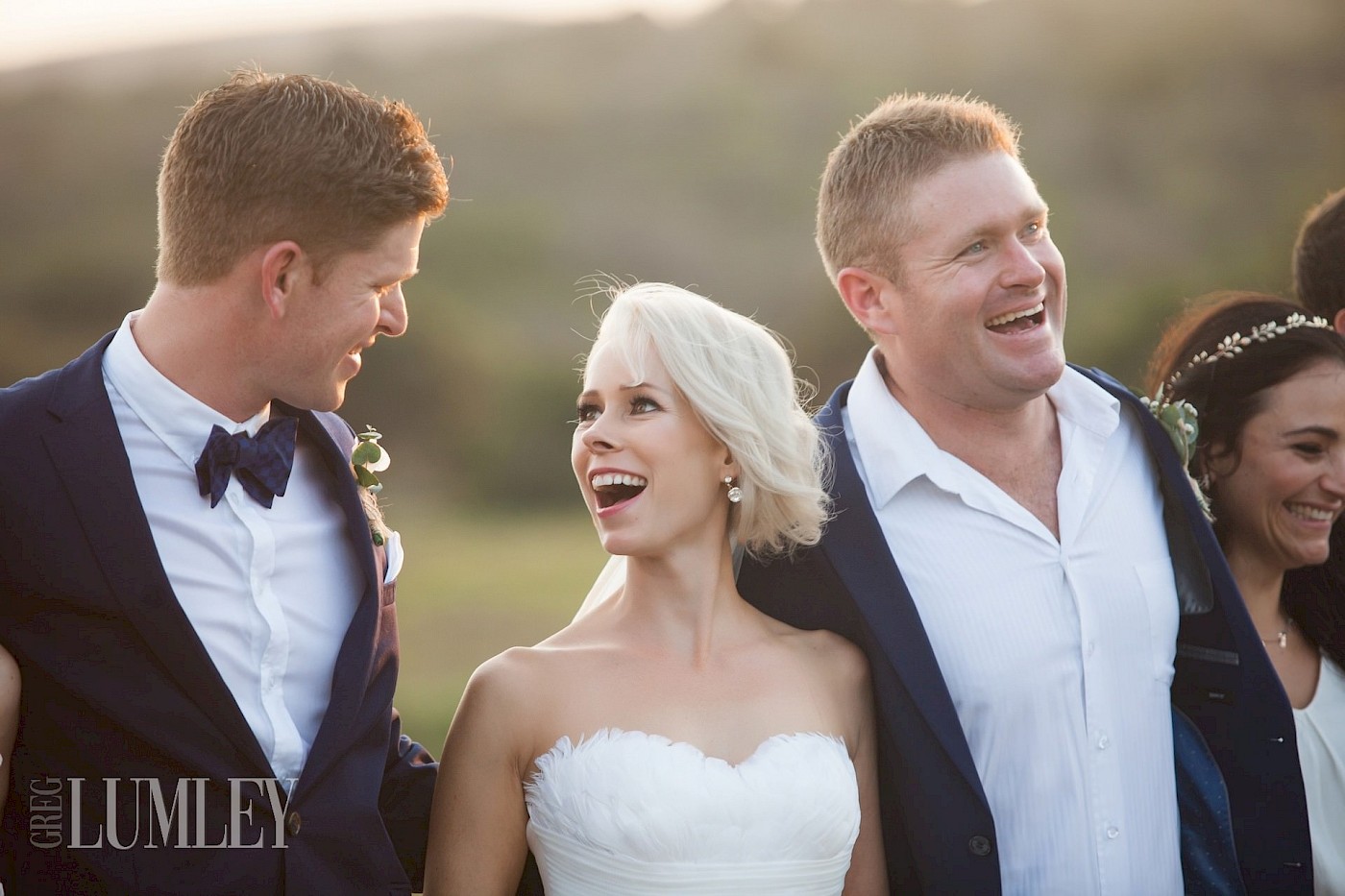 A lovely moment as a beautiful blonde bride bursts out laughing with her new husband during family photos.